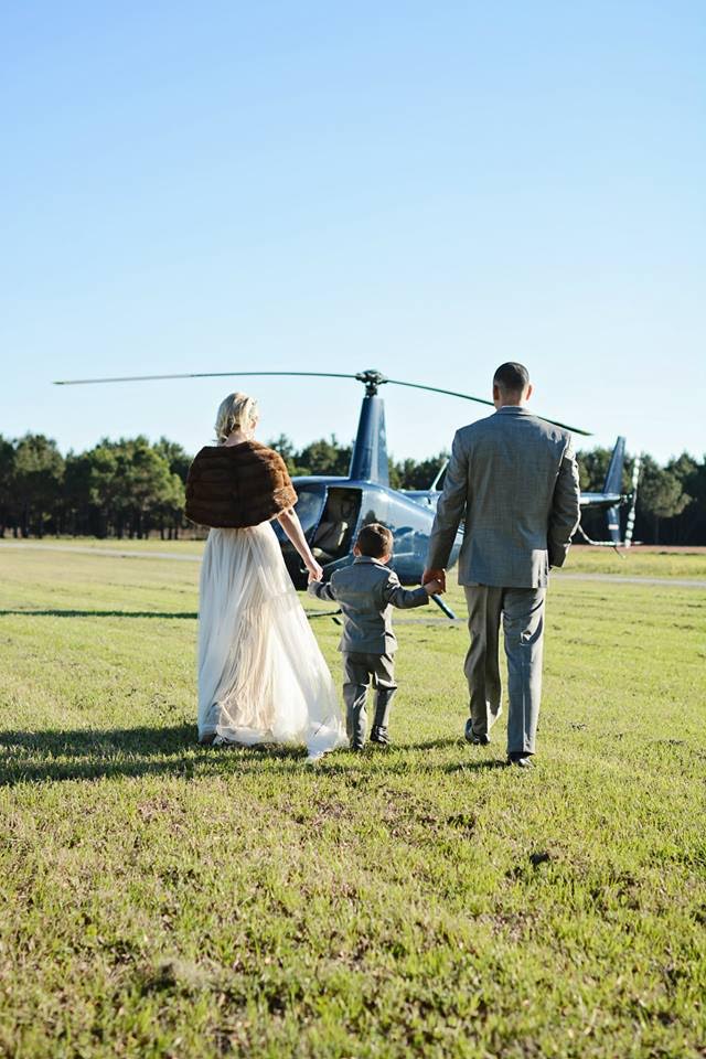The bride, groom, and their son in his tiny tuxedo walk towards a helicopter to whisk them away for an aerial tour of Charleston and the lowcountry.